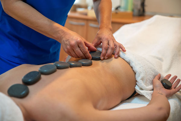 espalda de mujer recibiendo masaje naturopático con piedras calientes en Clínica Médico Estética Isabel Aragón