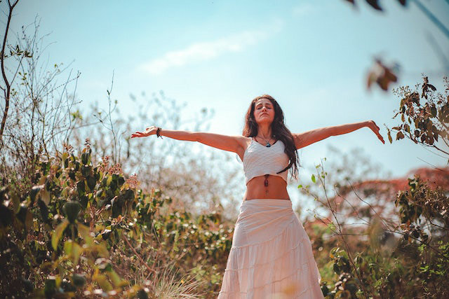 mujer levantando brazos en plena naturaleza